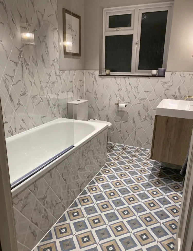 Completed family bathroom with new bath, basin and marble-effect tiling