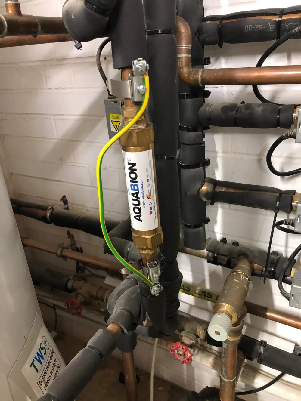 Plant room pipework with a water conditioner fitted to the incoming mains supply