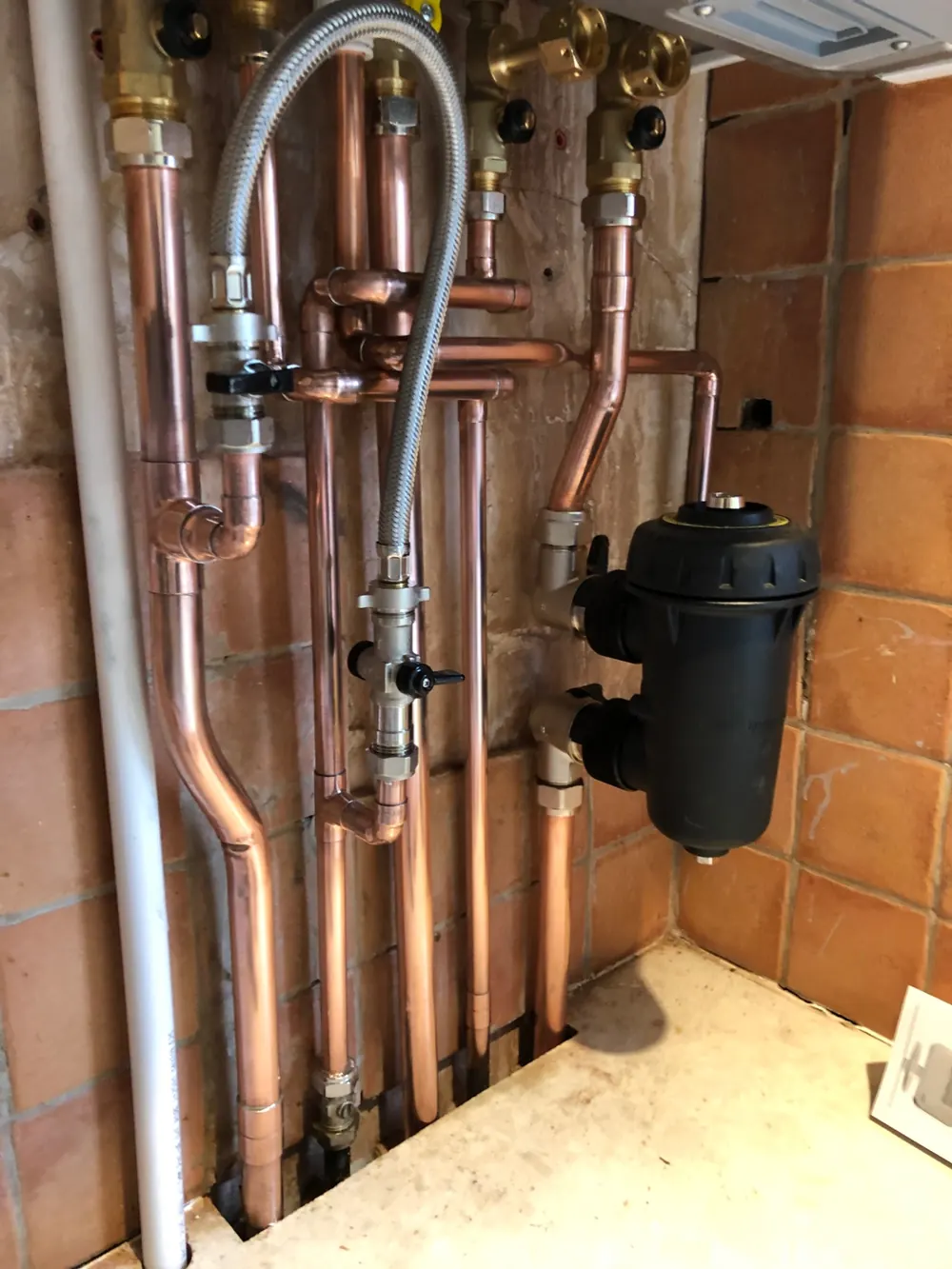 Copper boiler pipework with isolation valves and a magnetic system filter fitted in an airing cupboard